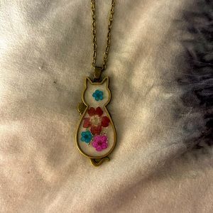 A cat shaped glass pendent with dried flowers inside